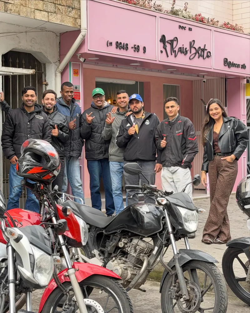 Os motoboys da doceria com a Thaís, na frente da loja rosa, com as motos estacionadas