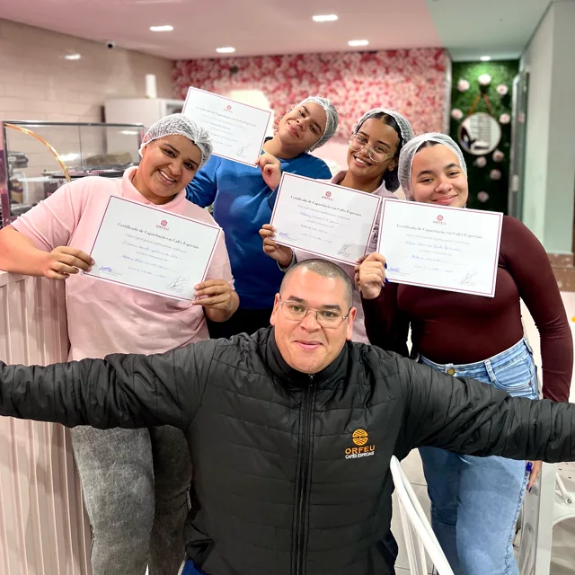 A equipe de touca mostrando os certificados do treinamento, com o instrutor na frente