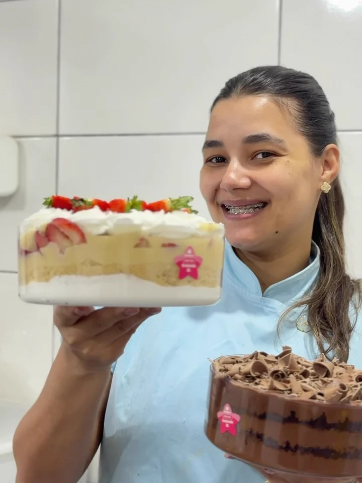 Thaís de dólmã na cozinha, mostrando um pavê de morango e outro de chocolate