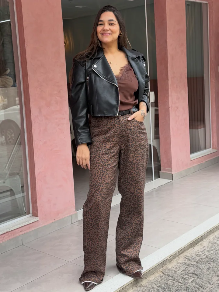 Thaís Brito de jaqueta de couro, sorrindo na porta da loja